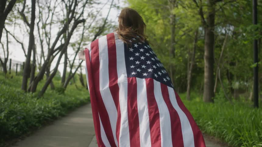 A woman is running with an american flag cape on