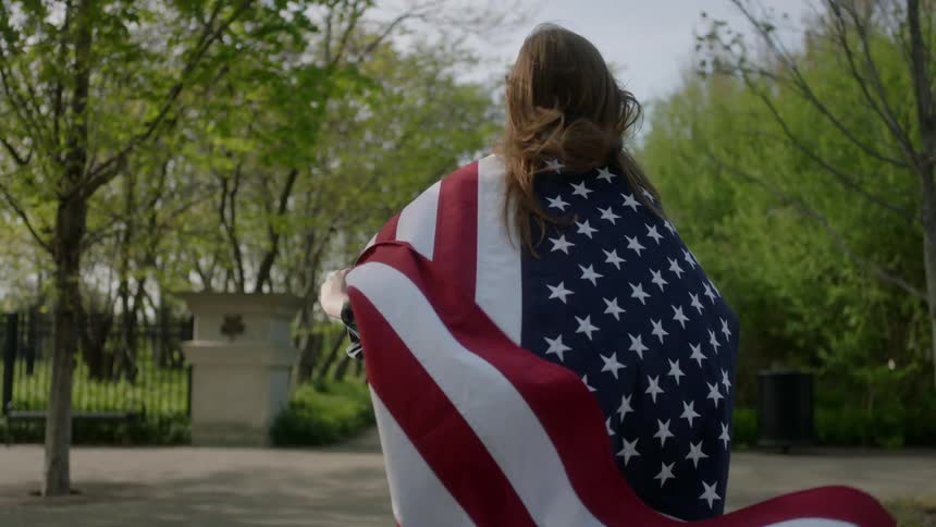 A woman is running with a flag around her neck blowing behind