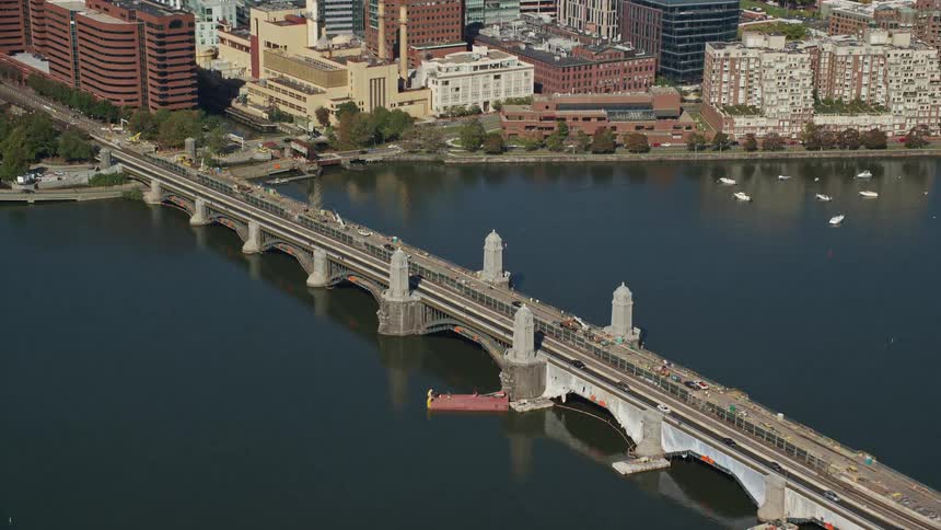 Traffic crosses bridge over river near marina and waterfront buildings