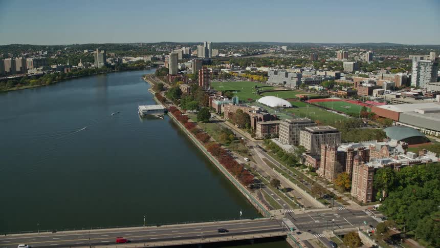 Traffic crosses river bridge near domed building and sports fields