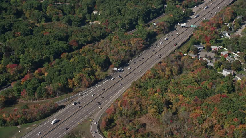 A large highway full of cars in the middle of a large forest