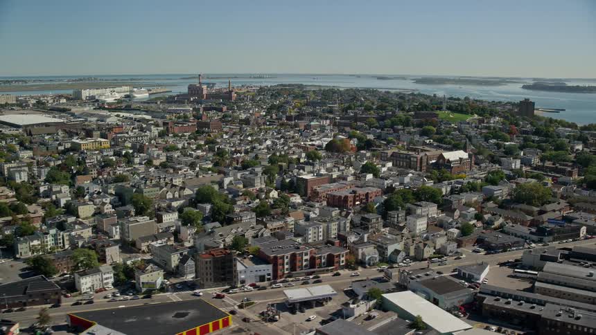 An urban region with many houses and in the background there is a sea