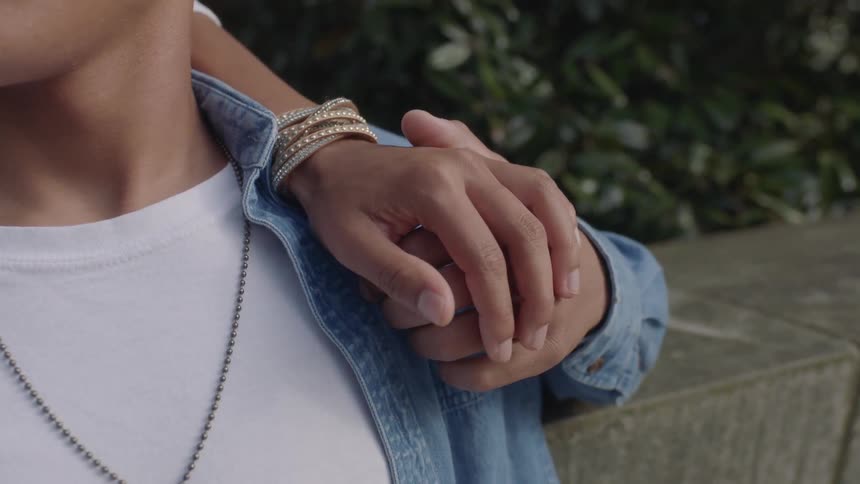 Two people are holding hands against a stone wall
