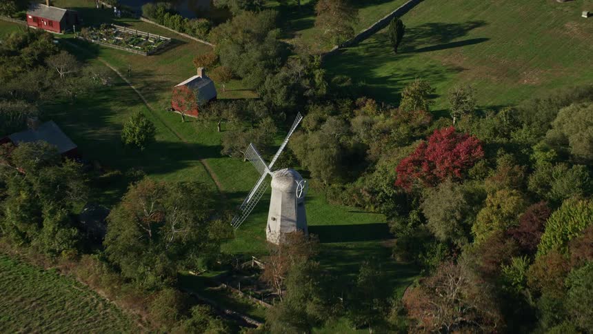 A small windmill in a rural area with lots of trees