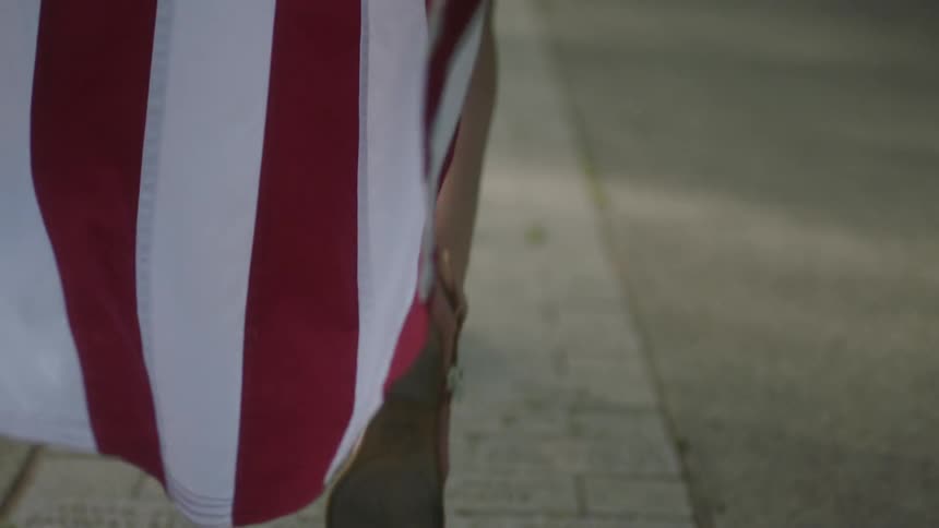 A person is running with an american flag hanging behind them