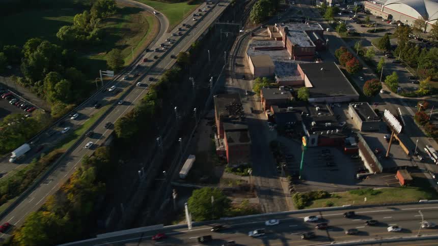 A daytime aerial view in the fall of busy city highways near a large building
