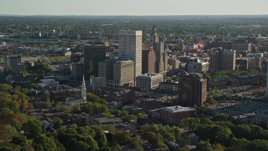 A region of a city with tall buildings and on the left side there is a small river
