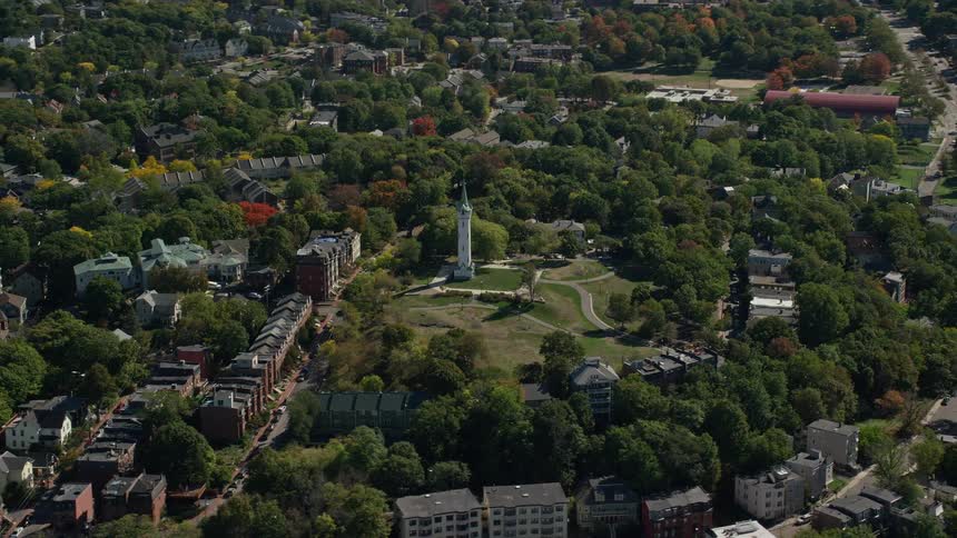 A towerlike structure in the center of a park surrounded by trees in a suburb