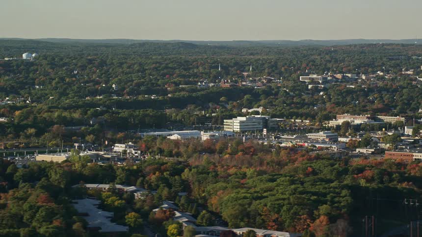 An aerial view of buildings in a rural neighborhood between fall trees