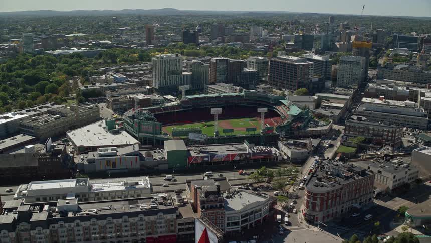 A grassy stadium in a city next to a busy highway