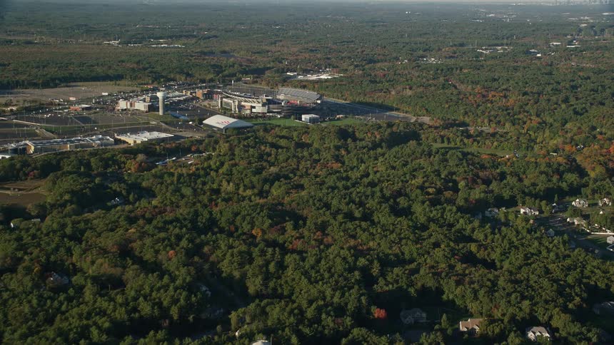 Aerial panorama of urban houses in green areas with a stadium on the horizon