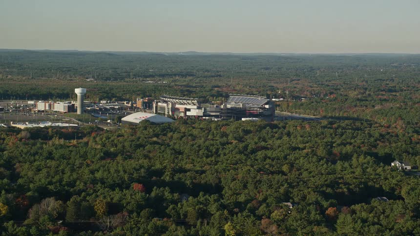 Trees in woods surrounding town with multiple sports fields are taking on fall foliage