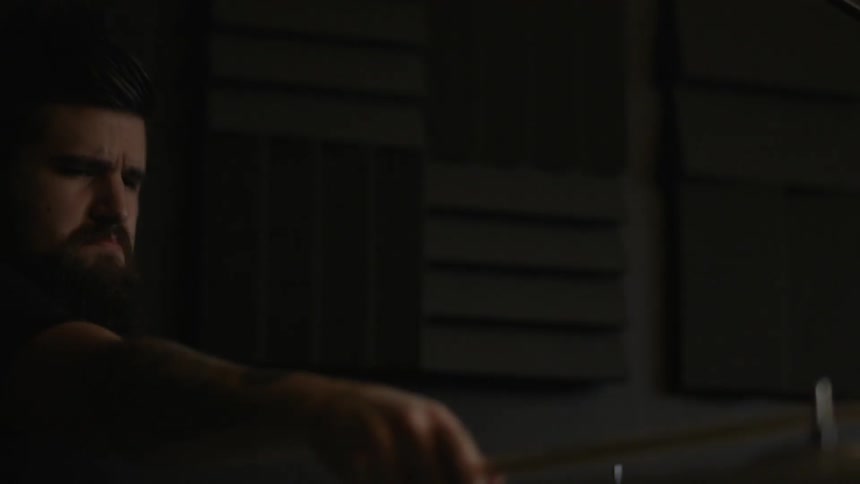 A man is playing drums in a dark area