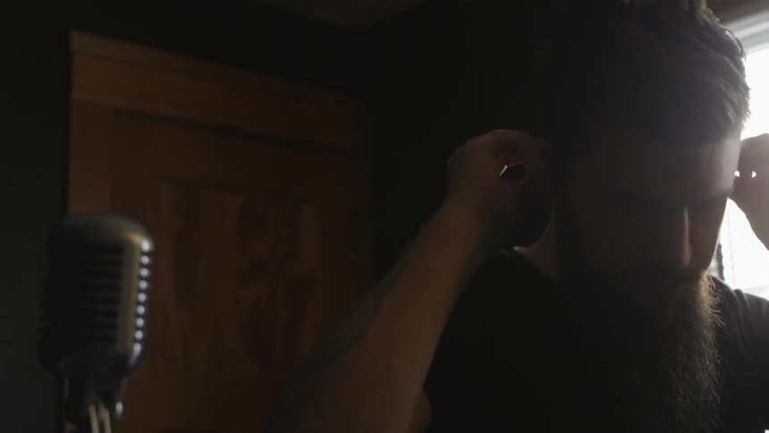 A man puts on earplugs and walks over to a mic