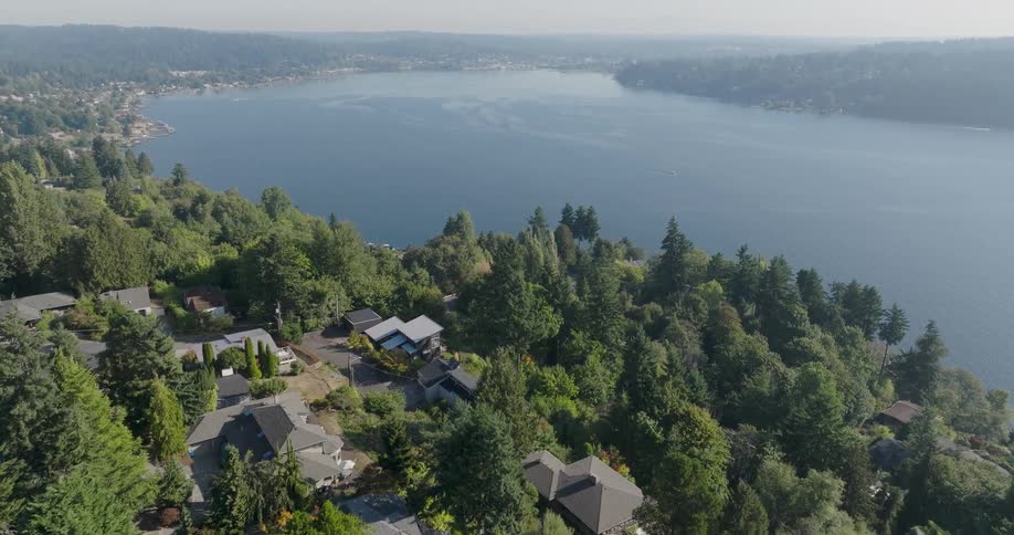 Homes dot a hillside that leads down to a shimmering lake