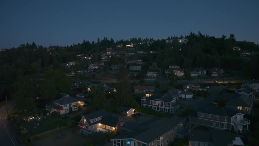 Low traverse above nice hillside homes under a summer twilight sky