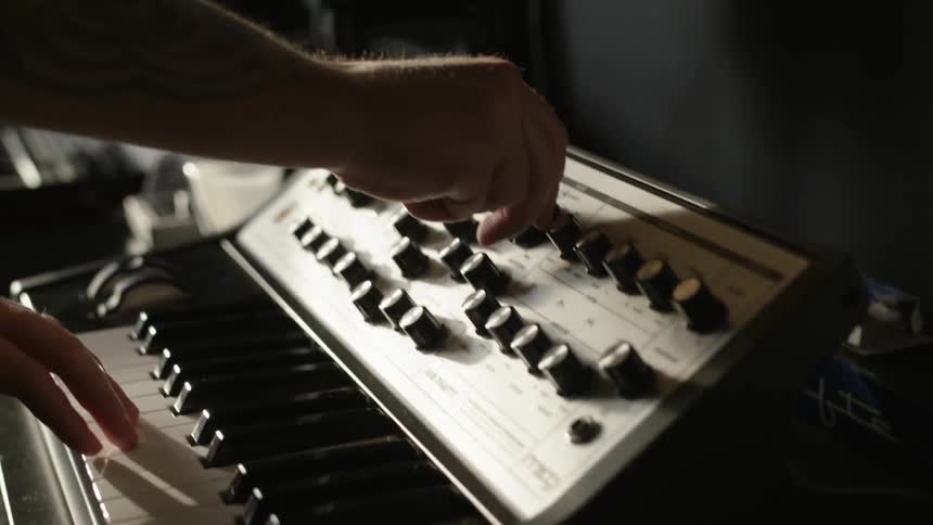A man walks over to a keyboard and presses switches