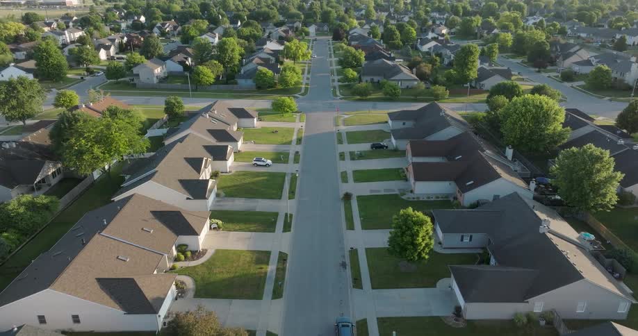 Morning light rakes across the manicured lawns of well kept homes in a residential neighborhood