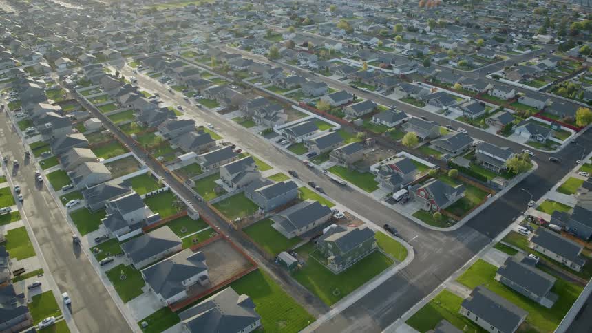 Pullback reveal of homes and streets along a peaceful neighborhood in the morning