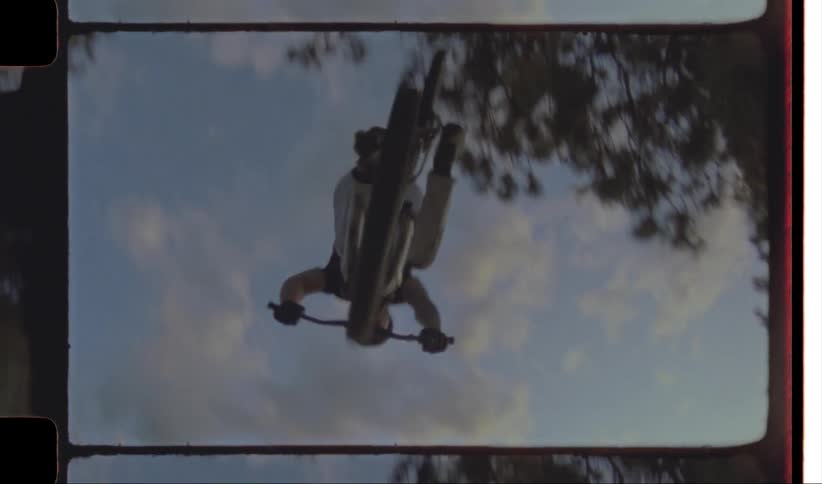 Man rides bicycle up ramp before performing flip in the air at bike course near lake