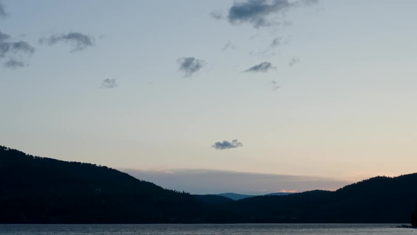 A view of the sea with a chain of mountains on the horizon under a sunrise sky