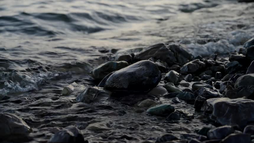 Waves roll over stones and pebbles along the shoreline