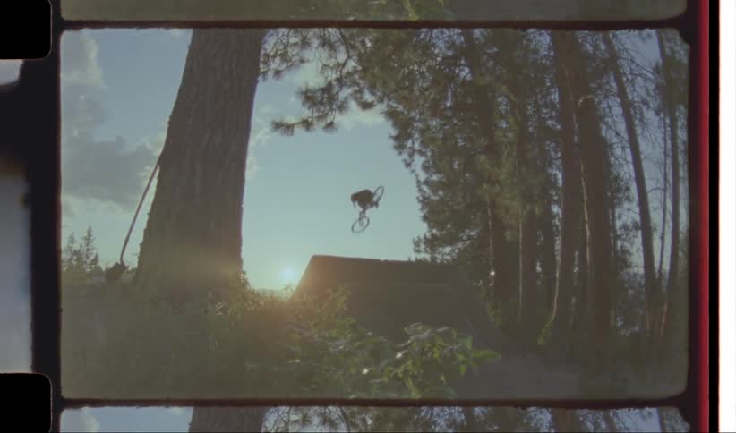 A man performing bicycle stunt over a barrier at sunset