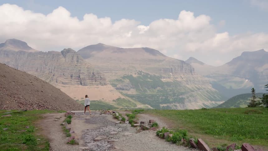 A woman walking along a rocky and wet mountain path
