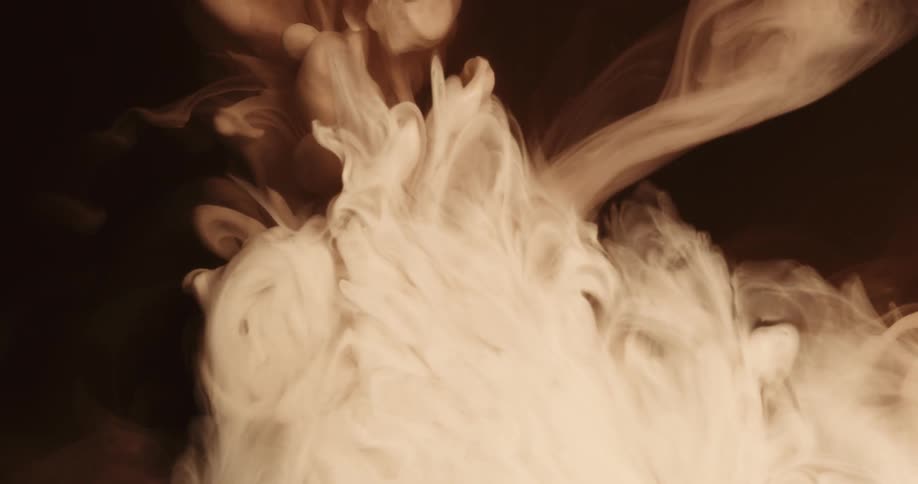 Dye flows into liquid forming cloudy mass in darkness