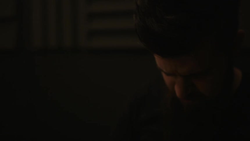 A man is looking down in a dark room