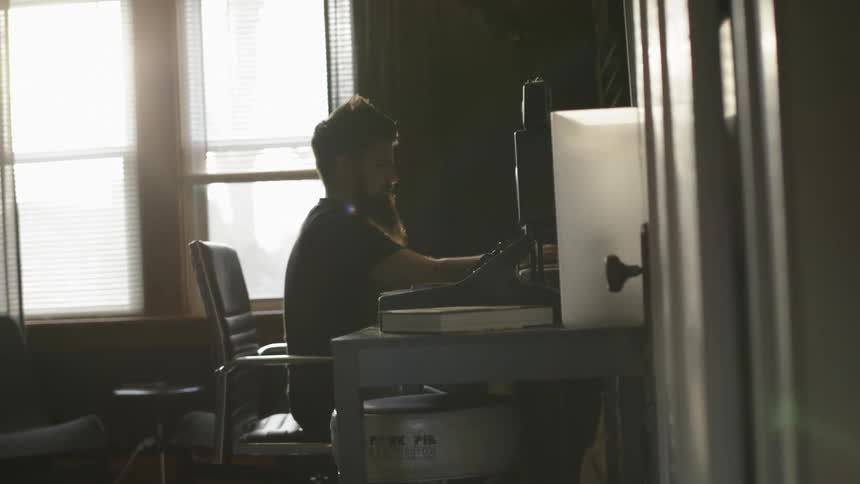 A man is sitting at a desk in bobbing his head