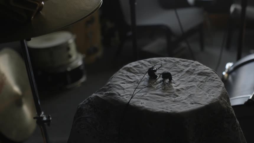 A pair of earbuds are on top of a drum