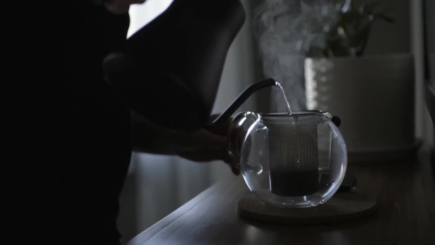 A person pours hot water into a pitcher
