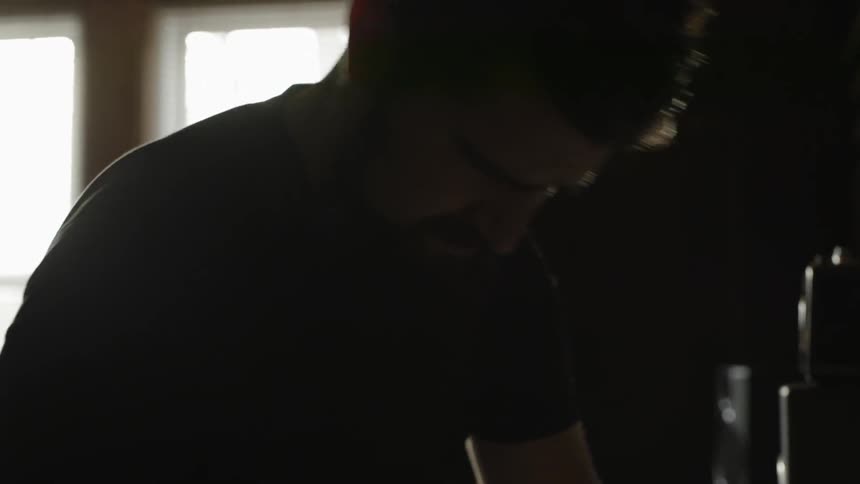 A man is moving around in a dark room bobbing his head