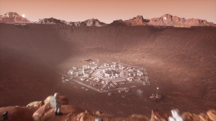 Astronauts stand on the edge of a cliff looking at a base inside a crater on mars