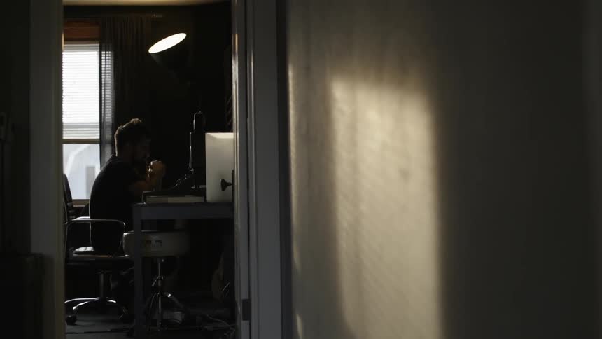 A man is sitting at a desk in a dark room ahead
