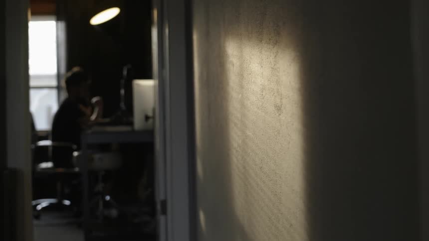 Through the doorway a man is sitting bobbing his head
