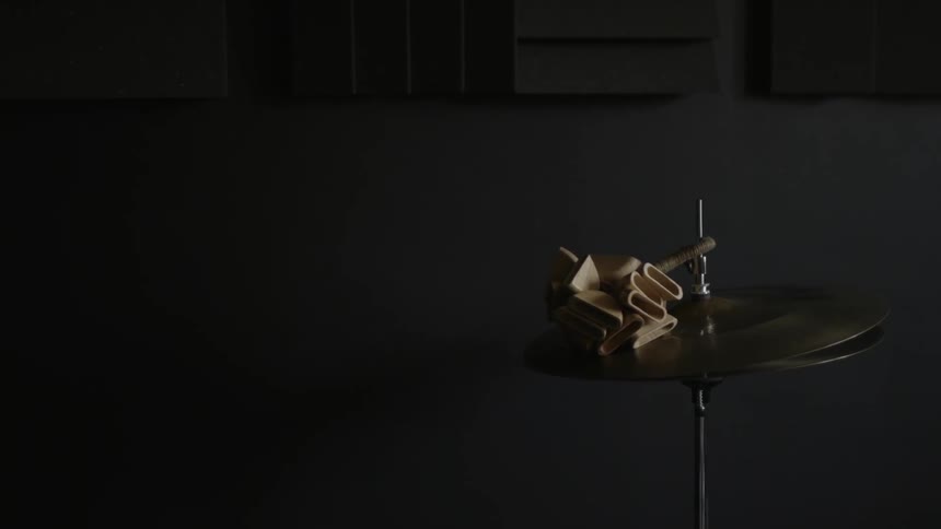 A drum cymbal sits in a dark area
