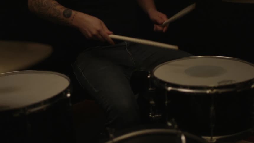 A person is playing drums in a dark area