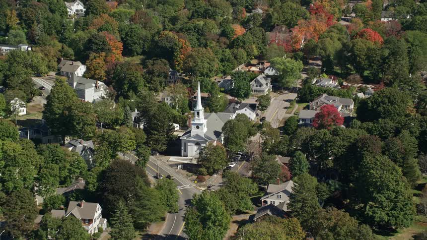 Woods surround houses and church in small town in autumn