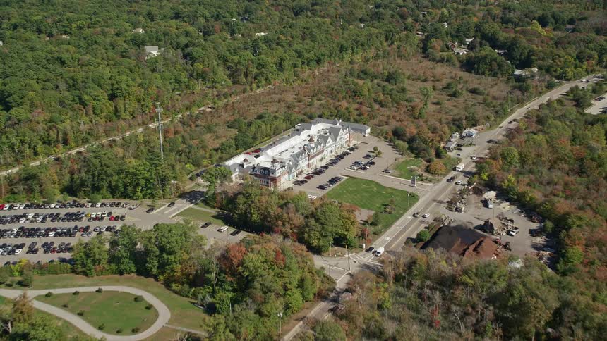 Aerial view of building with grey roof parking lot and trees