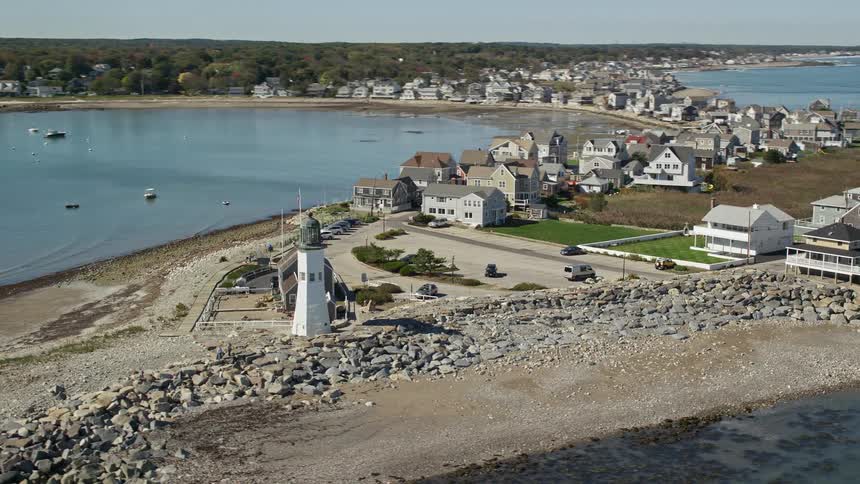 Aerial view of lighthouse and homes on rocky coastal peninsula
