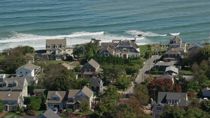 Estate homes stand in a neighborhood along the coast as waves roll into shore