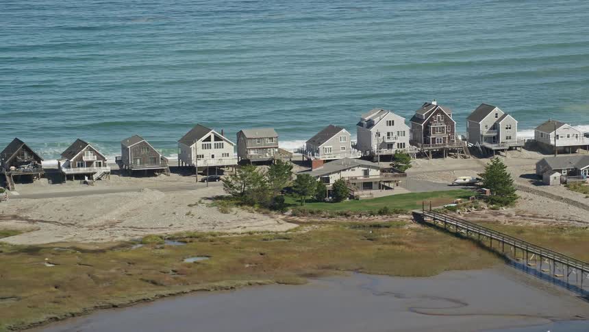 Houses occupy narrow strip of land between river and beach