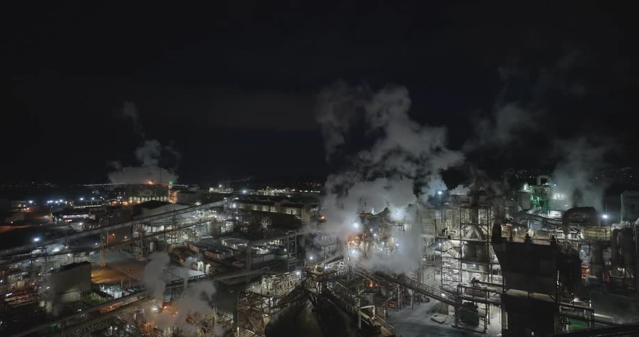 Smoke rises from manufacturing complex at night