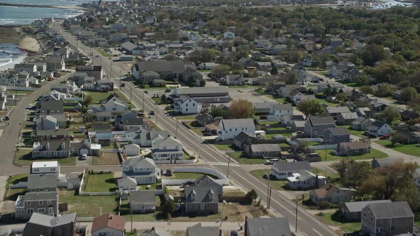 Traffic moves on the neighborhood streets of a coastal community as waves roll into shore