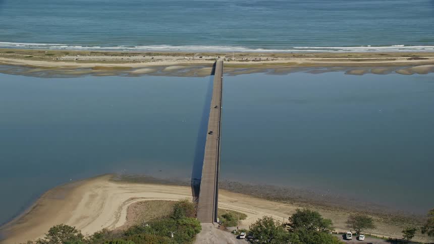 Traffic moves across the powder point bridge to the beach as waves roll into shore