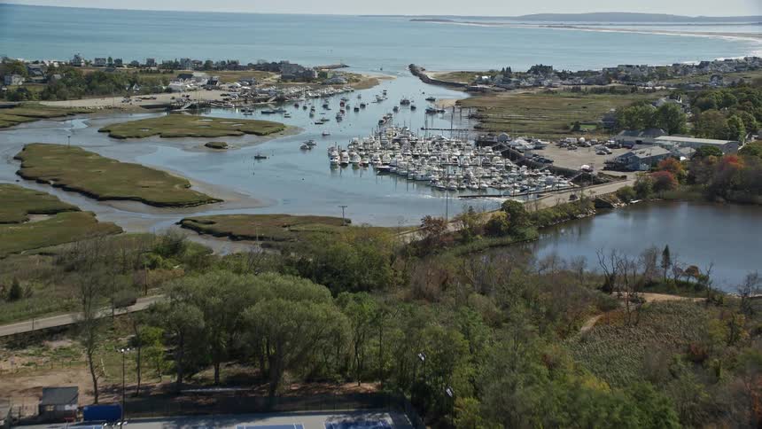 Flight over a marina peer near a suburb by the ocean