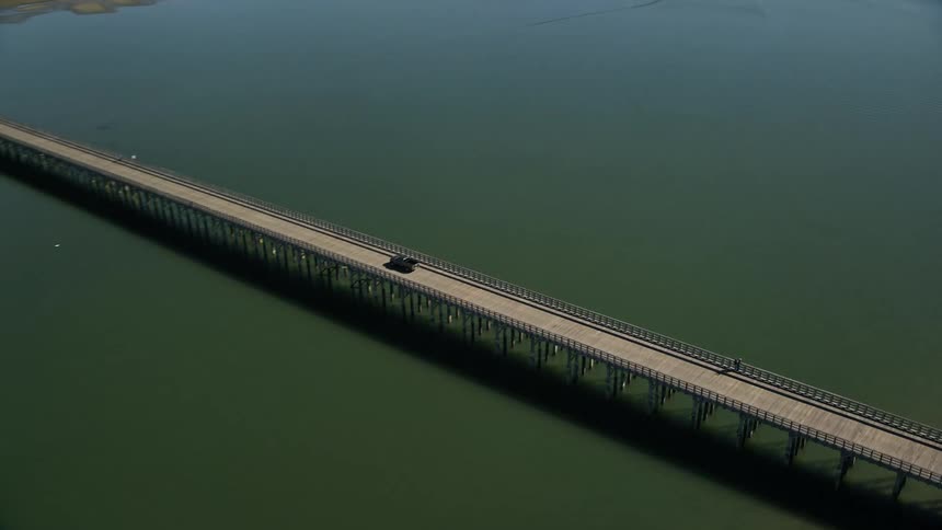 Traffic moves across powder point bridge to the beach as waves roll into shore