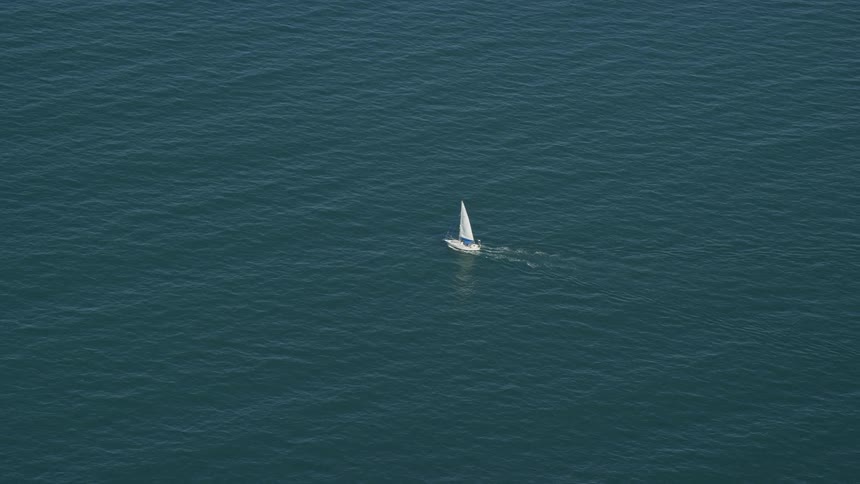 Sailboat leaves wake while sailing across ocean